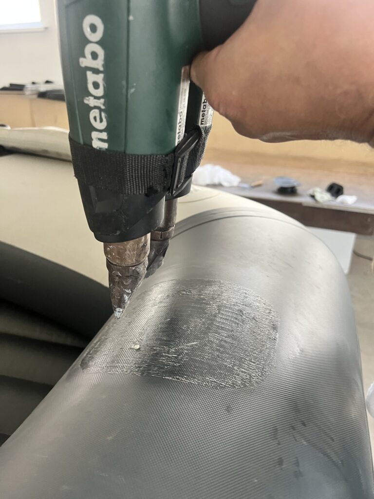 Прогрев клеевого слоя строительным феном на баллоне лодки ПВХ перед прикаткой заплаты